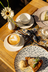 Coffee and desserts pastries on table with flowers and glasses in cafe