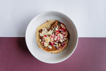 Brownie dessert decorated with cream, cherry jam, and almond flakes