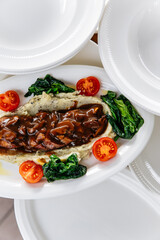 Sliced ​​duck breast with sauce and mashed potatoes with vegetables on a plate