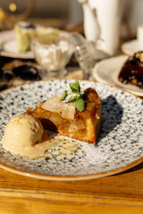 Apple strudel with ice cream in a plate on a restaurant table under the sun