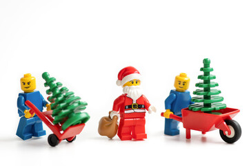 Obraz premium Miniature figurines with Christmas trees and Santa Claus on a white background.