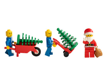 Obraz premium Santa Claus and miniature figurines with a wheelbarrow and Christmas tree on a white background