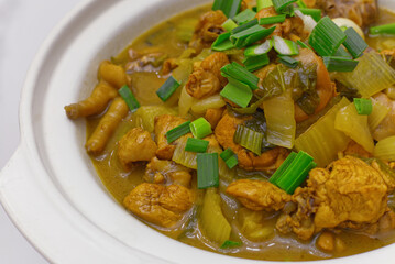 a rustic chicken stew or braised dish featuring pieces of chicken and celery in a savory yellow or turmeric-based sauce