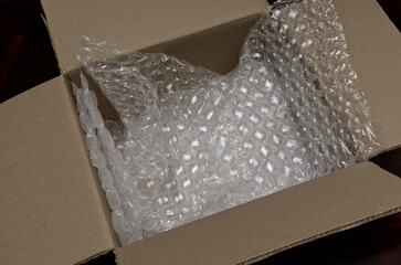 an open brown cardboard box showing clear plastic bubble wrap used as protective packaging material inside. 