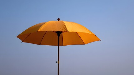 Obraz premium A vibrant yellow umbrella stands open against a clear blue sky