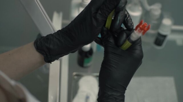 Two joined syringes in the hands beautician, medic. Doctor in black latex gloves prepares before a cosmetic procedure. Close up.