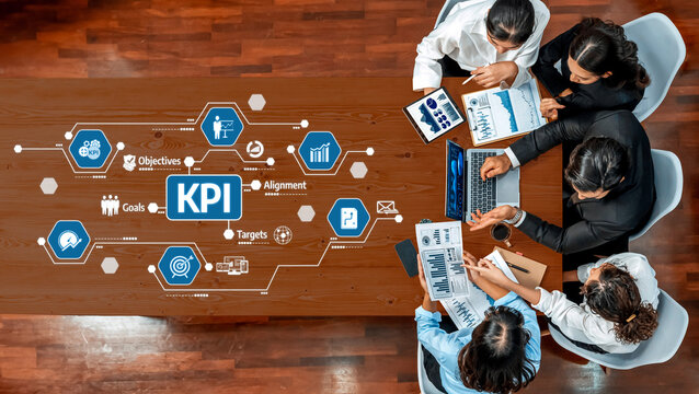 A diverse team collaborates at a wooden table, analyzing key performance indicators (KPI) and metrics to enhance business strategy and achieve objectives. Amity