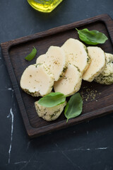 Sliced halloumi cheese on a black wooden serving tray, vertical shot on a black marble surface, middle close-up
