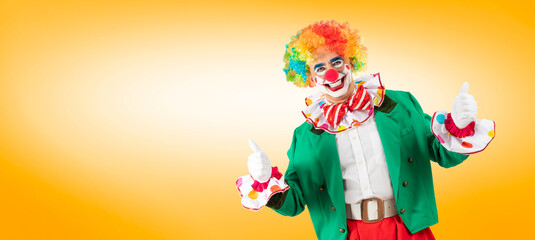 Funny clown thumbs up, man entertainer as Joker in a suit and wig, with clown whiteface makeup. Trickster, jester, pantomime, mime, and a professional actor at events.
