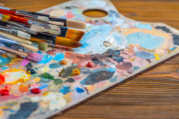 Old used brushes in an artist's studio, palette with multi-colored spots of oil or acrylic paint