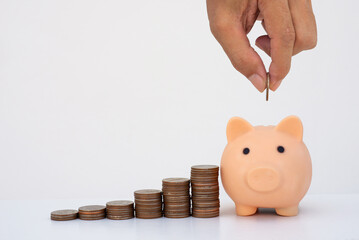 money saving concept. business man han dropped coin on piggy bank with coin stack on white background. money matters tips to investment and business financial banking for Financial Wellness.