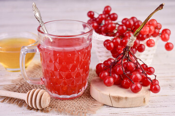 Medicinal drink or fruit drink made from viburnum berries with honey on a white wooden background.
