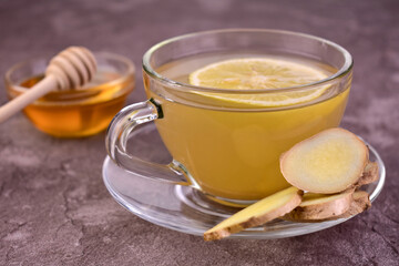 Ginger tea in a transparent cup on a gray background. Close-up.
