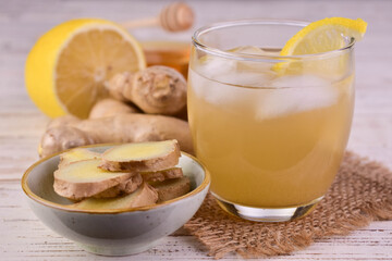 Ginger tea with ice, honey and lemon in a glass. A refreshing vitamin drink.
