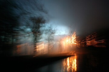 Abstract light streaks in forest at dusk with water reflection