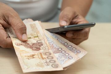 Asian woman counting Thai baht banknote money, investment economy, accounting business and banking.