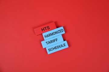 A colorful stack of wooden blocks labeled HTS, Harmonized, Tariff, and Schedule against an red backdrop, symbolizing international trade, customs classification.