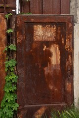 Old rusty door gate plate overgrown