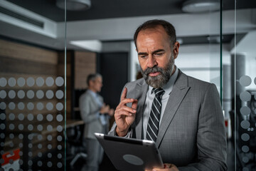 Mature businessman working with tablet in modern office