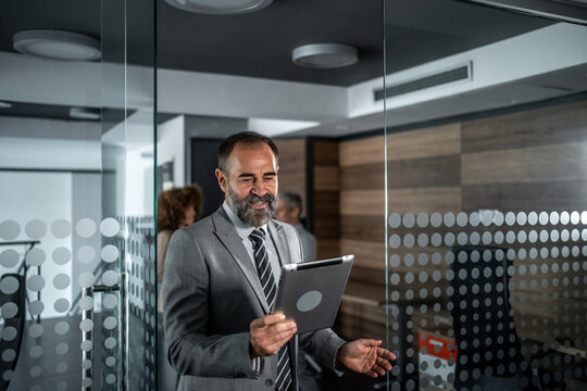 Businessman enjoying tablet in modern office corridor