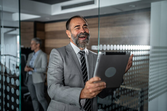 Senior businessman laughing during video call in modern office
