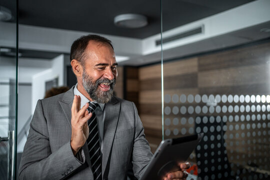 Mature businessman waving during video call on tablet