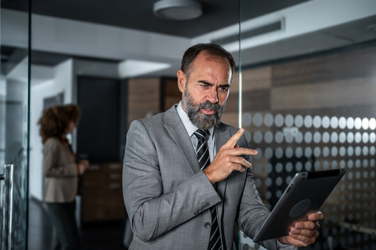 Mature businessman concentrating on digital tablet in office