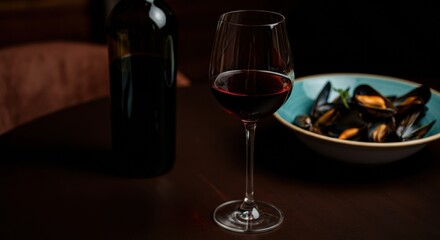 Wine glass beside moules marini&egrave;res in a cozy seafood setting with wine