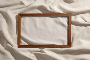 Empty wooden frame lying on draped linen surface for refined artistic mock up styling