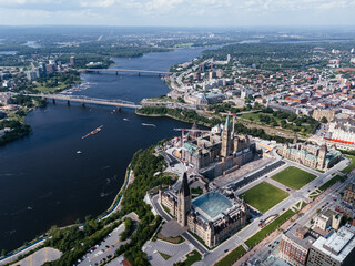Fototapeta premium Drone view of Canadian Parliament, Parliament Hill, House of Commons, and East Block in downtown of Ottawa and river in a sunny day, Canada.