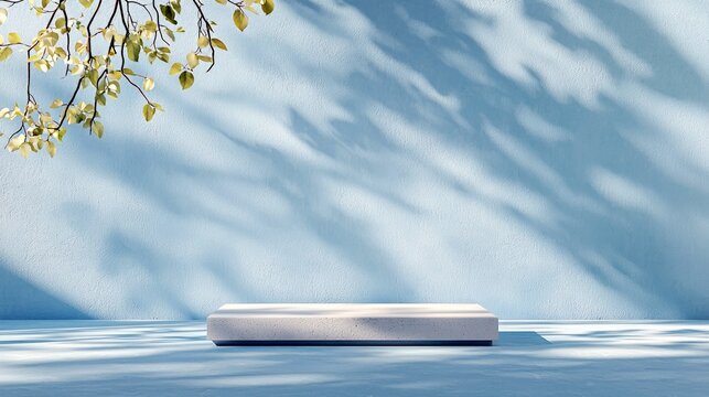 A minimalist scene featuring a rectangular stone pedestal in the foreground, bathed in dappled sunlight. A textured blue wall serves as the background, with dra