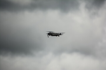 Drone with camera flying against cloudy sky. The image highlights modern aerial technology, stability, and unmanned flight capability in outdoor conditions.