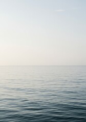 Expansive view of an empty ocean surface meeting a cloudless, pale sky, creating a minimalist, neutral backdrop for design or conceptual projects ,empty ,mood ,horizon
