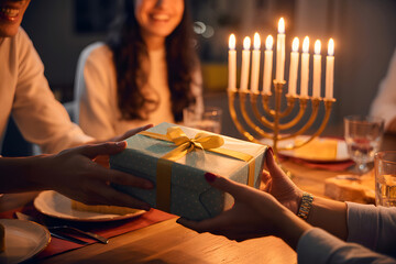 Family celebrating hanukkah with gifts and menorah candlelight