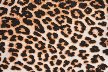 A full-frame shot captures the detailed, repeating pattern of a classic black and brown leopard print textile