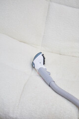 Vacuum cleaner on the white sofa. 