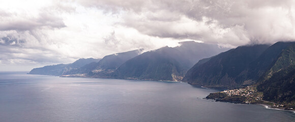 Dramatic cloudy horizon over quiet sea and charming cliffside settlement