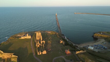 Tynemouth England: 16th August 2025: Tynemouth Priory and Castle during a stunning sunset with coastal views, ancient ruins and Tynemouth Pier. Drone view during golden hour