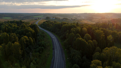 Fototapeta premium a highway in the mountains at sunset with a car driving along it