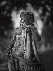 Weathered stone cherub statue at Goat Gate Cemetery in Bratislava, photographed in soft black and white.