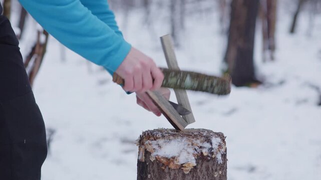 Batoning pine wood with a knife in a snowy Scandinavian forest