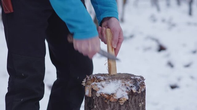Making feather sticks from pine wood in a winter forest for bushcraft skills