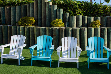 four Adirondack chairs colors white and aqua blue on green turf