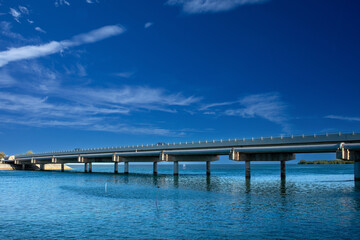 bridge going over the magnificent ocean under the beautiful blue sky and clouds