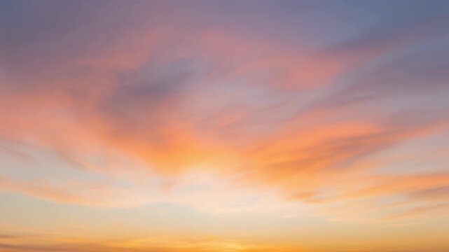 Time lapse video of colorful clouds drifting slowly and changing colors at sunrise or sunset. Soft orange, pink and purple hues in the sky.