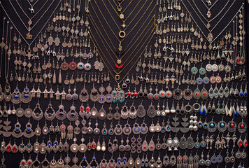 Collection of intricate silver jewelry displayed on a black background, featuring various earrings, necklaces, and pendants, showcasing craftsmanship and artistic design