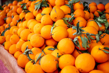 Vibrant pile of fresh oranges with green leaves displayed at a market, showcasing the natural beauty and abundance of citrus fruits in a colorful arrangement