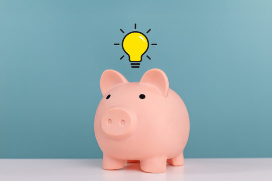 Piggy bank, invest, interest rates, dividends and saving, Idea for saving and investment. Piggy bank with virtual lightbulb on the table in the office