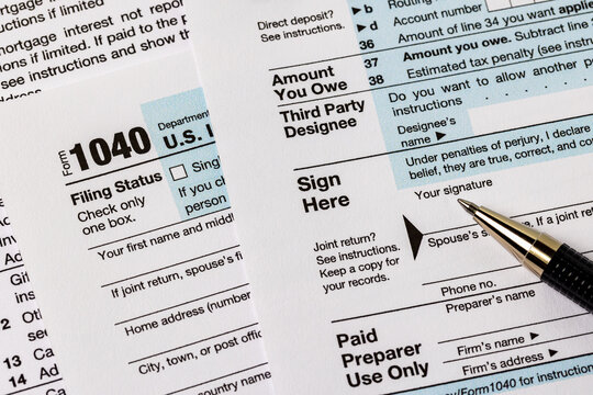 Signing 1040 federal income tax form. Tax preparation, fraud, and filing taxes concept.