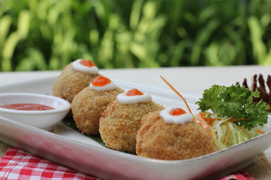 Four round bread rolls on a plate, topped with red sauce and mayonnaise.